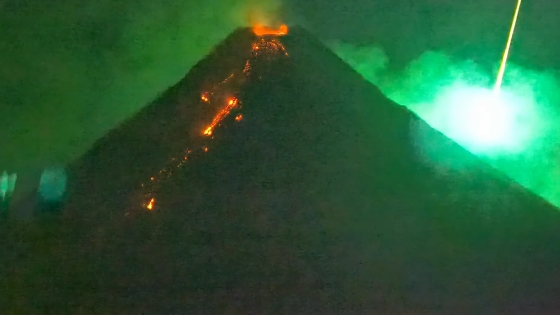 噴火中の火山の背後を鮮やかな緑色の火球が横切る瞬間が撮影される